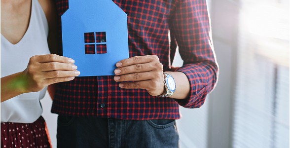 Couple holding a small blue house cutout